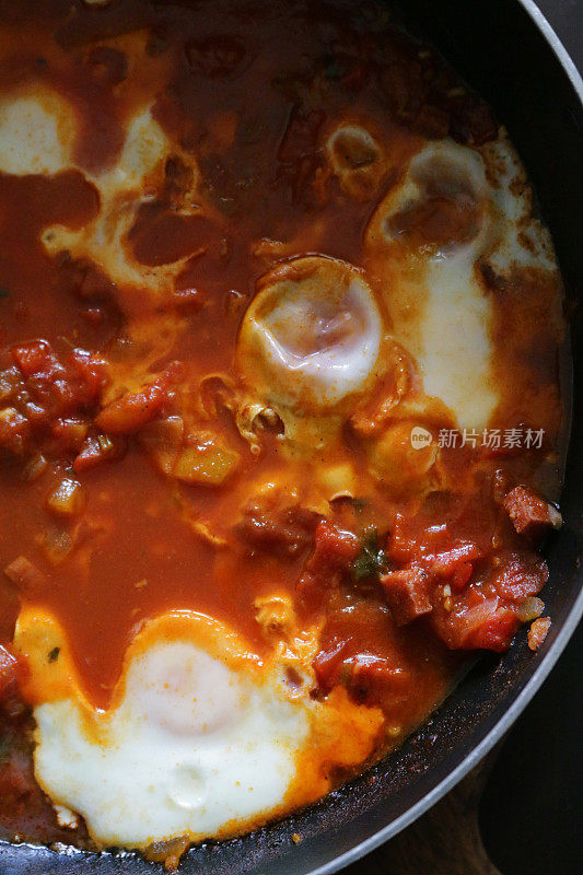 地中海健康早餐shakshouka / shakshuka / chakchouka在平底锅里，鸡蛋煮在西红柿、辣椒、洋葱、橄榄油和大蒜的酱汁里